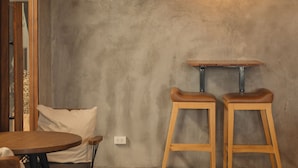A room with a round wooden table, two wooden stools, and a hanging light fixture. - Hostel Urby (Bangkok)