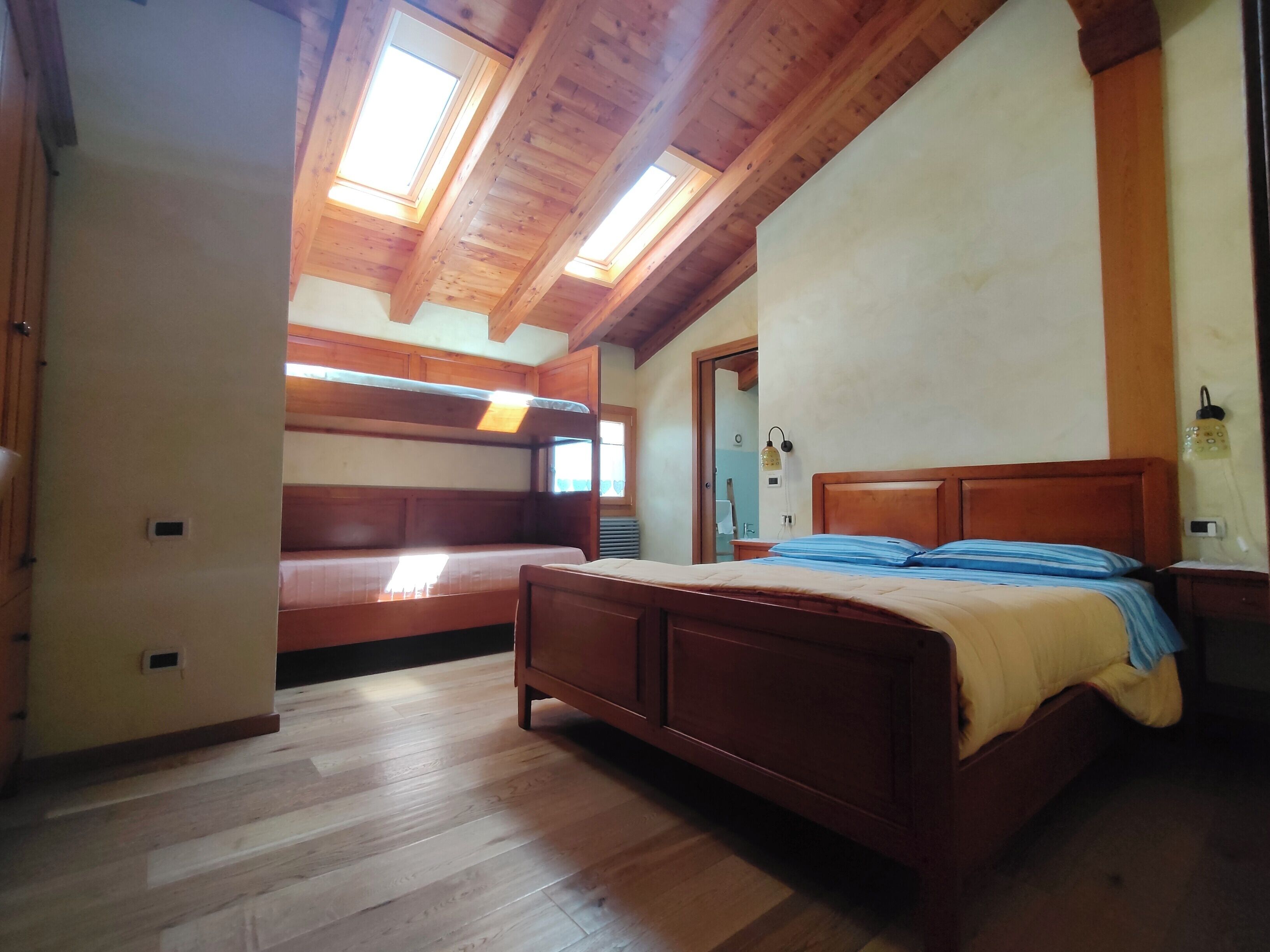 A bedroom with a wooden bed, a bench, and a skylight.