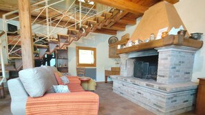 A cozy living room with a stone fireplace, a wooden staircase, and a comfortable sofa.
