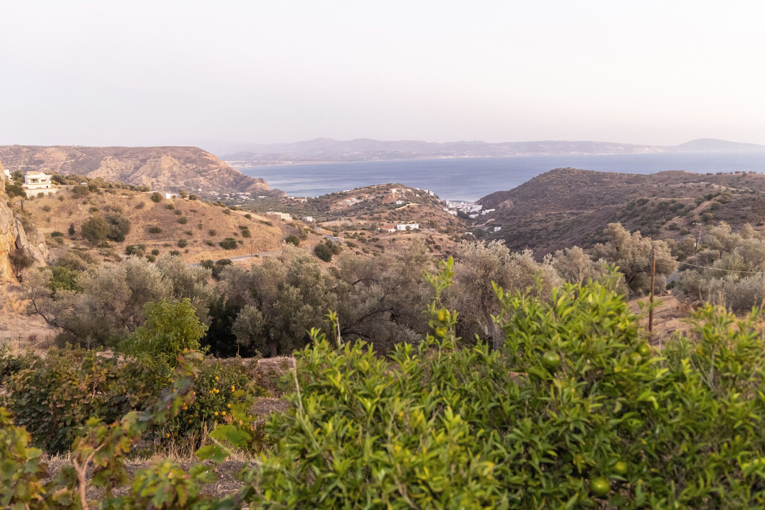 A coastal landscape with buildings on a hillside, overlooking the sea.