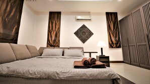 A modern hotel room with a large bed, a wall-mounted air conditioner, and a decorative wall piece. - Hansa Paradise Hill Pool Villa (Pattaya)