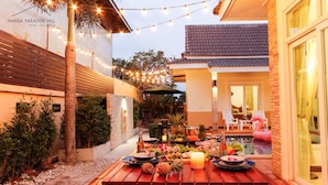 A patio with a dining setup featuring a table, chairs, and a pool. - Hansa Paradise Hill Pool Villa (Pattaya)