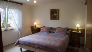 Una camera da letto ordinata con un letto grande, due comodini con lampade, un quadro appeso al muro e una finestra con tende.