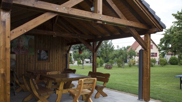 Un padiglione in legno all'aperto con tavolo da picnic e panche.