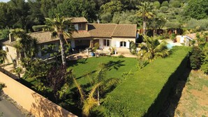Une maison à deux étages, dotée d’un toit en tuiles, entourée d’une végétation luxuriante et d’une pelouse bien entretenue.