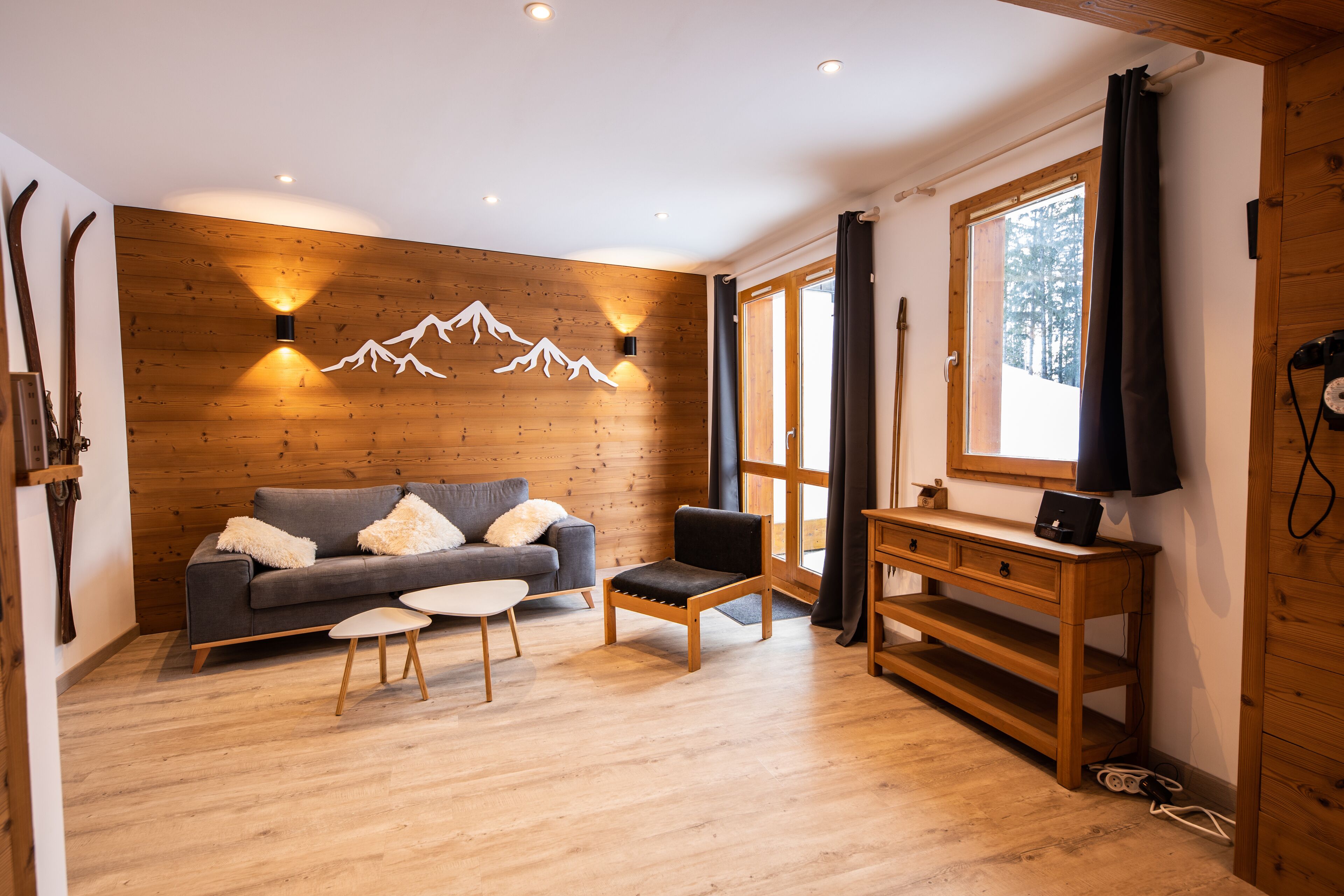 Een gezellige woonkamer met een houten wand, een bank, een klein tafeltje en een stoel.