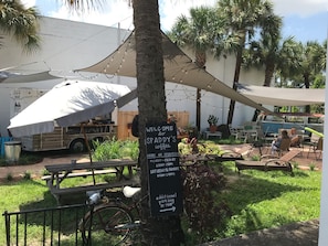 Un café con mesas al aire libre, un cartel y una bicicleta estacionada cerca.