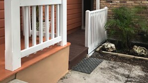 Een huis met een veranda, een bakstenen muur en een witte balustrade.