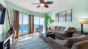 A living room with a view of the ocean, a ceiling fan, a large plant, and a sofa. - Gulf Front Condo with Luxury Furnishings and Beach Chairs  (Pensacola Beach)