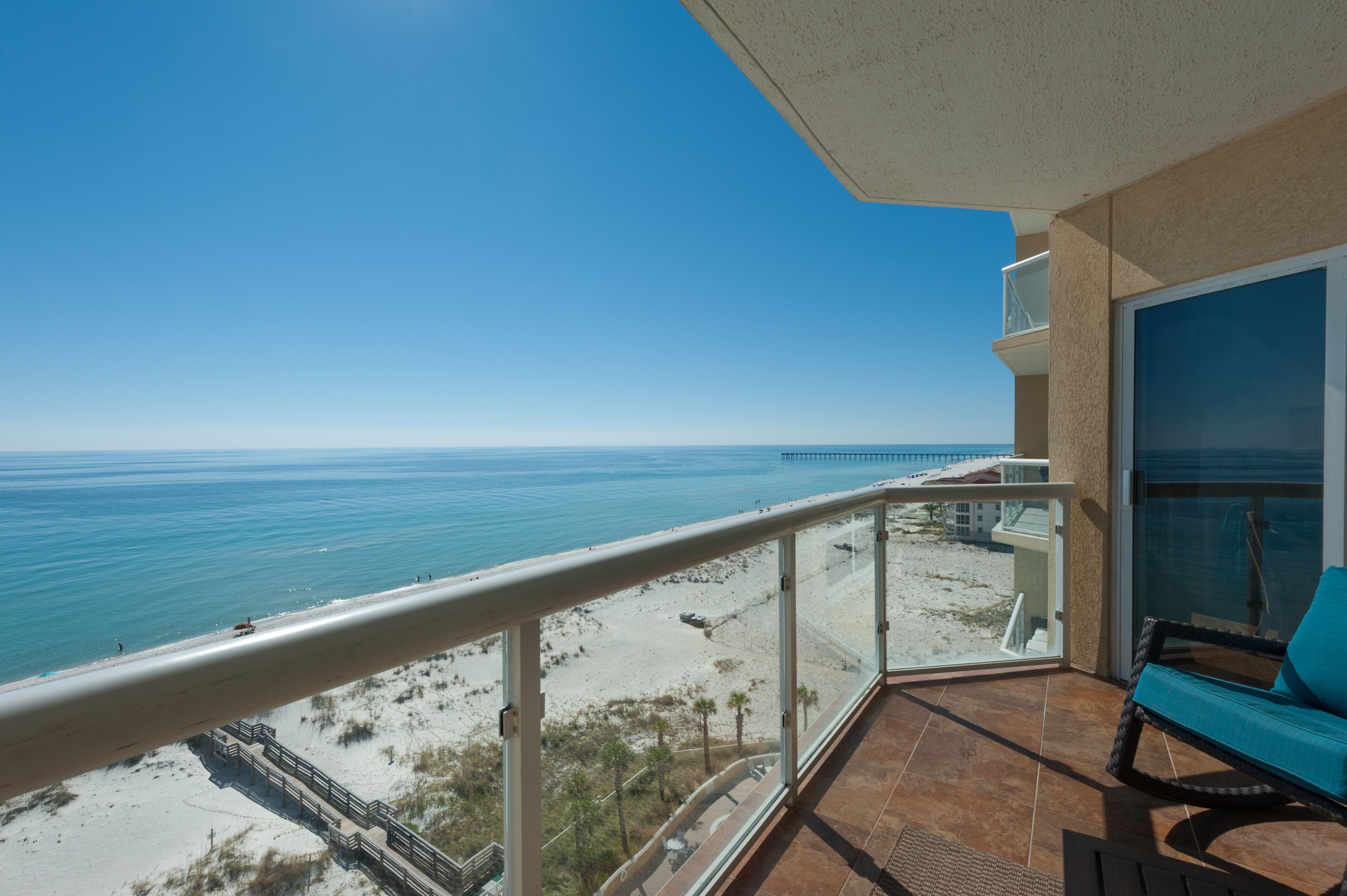 A balcony with a view of the beach and ocean.