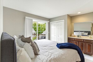 A bedroom with a bed, a dresser, a mirror, and a door leading to a balcony.