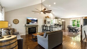A spacious living room with a fireplace, a ceiling fan, a television, and a dining area with chairs and a table. - "On the Rocks"  Bourbon Trail Getaway (Taylorsville)