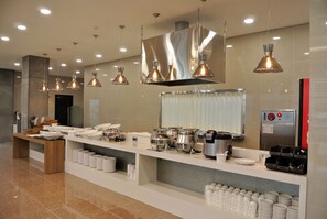 A buffet setup with various food containers, a coffee machine, and a refrigerator. - Jeju Noblesse Tourist Hotel (Jeju City)