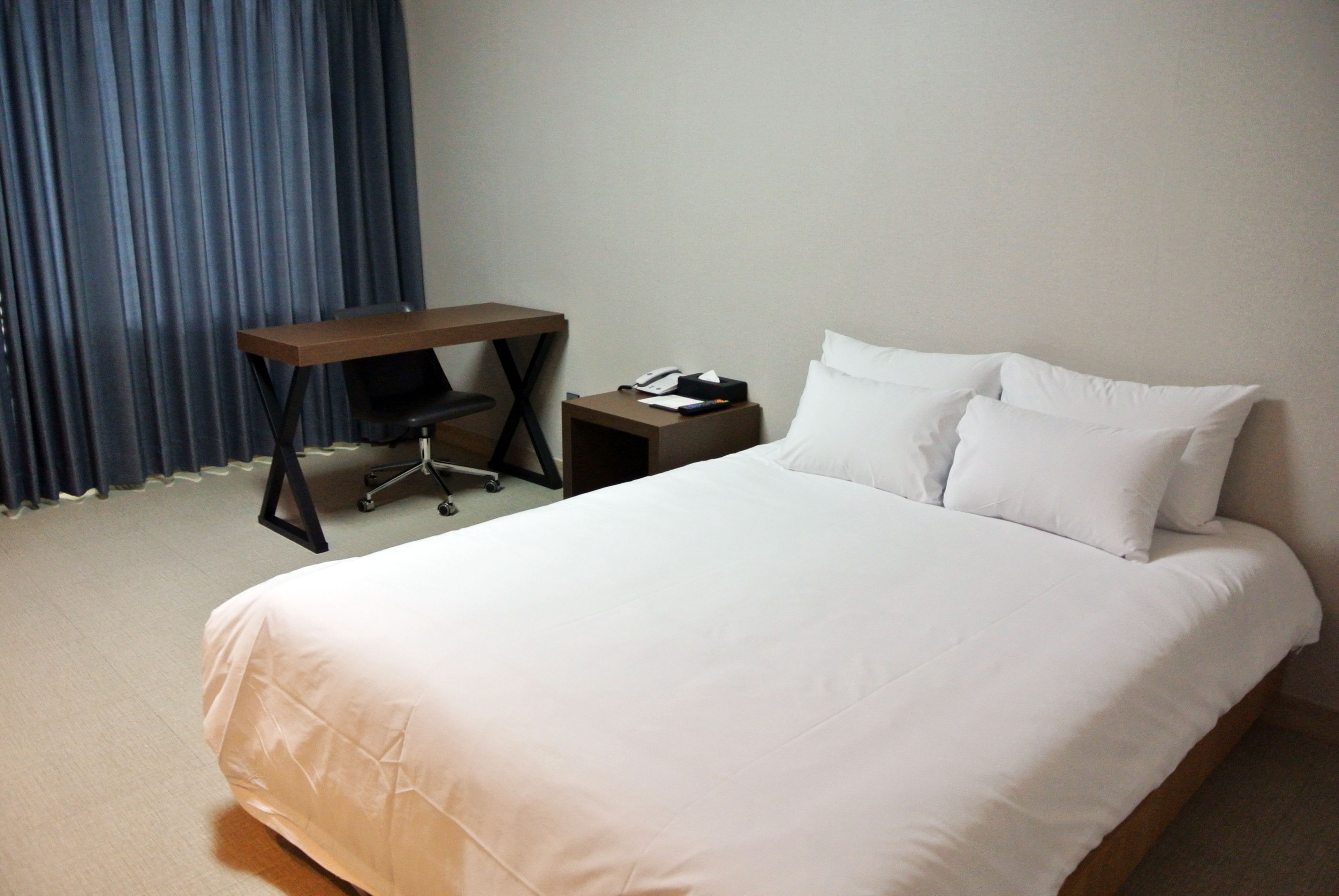 A hotel room with a large bed, a desk, and a chair.