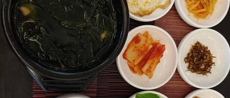 A table with various dishes including a bowl of rice, a bowl of soup, and several small dishes with different foods.