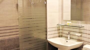Ein modernes Badezimmer mit einer Duschkabine, einem weißen Waschbecken und einer Toilette.