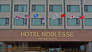 Un hotel con varias banderas, incluyendo la bandera estadounidense, y el nombre "HOTEL NOBLESSE" exhibido de forma destacada.