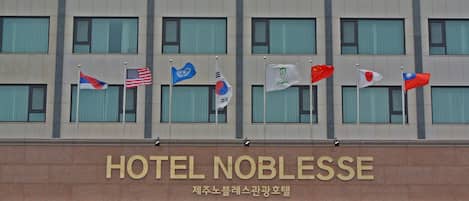 A hotel with multiple flags, including the American flag, and the name "HOTEL NOBLESSE" displayed prominently.