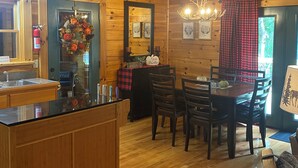 A wooden cabin interior with a kitchen, dining area, and a cozy living space. - Two bedroom cabin, King Beds, WI-FI, hot tub, pool, views (Pigeon Forge)