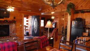 A cozy cabin interior with a fireplace, wooden walls, a dining area, and a kitchen. - Two bedroom cabin, King Beds, WI-FI, hot tub, pool, views (Pigeon Forge)