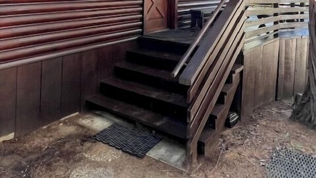 A wooden cabin with a porch, a staircase, and a door with a window.
