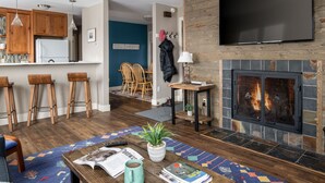 Ein modernes Wohnzimmer mit Kamin, Holzböden und einem flachbildfernseher, der an einer Holzwand befestigt ist.