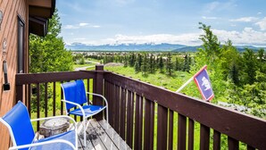 Eine Holzterrasse mit blauen Stühlen mit Blick auf eine gebirgige Landschaft.