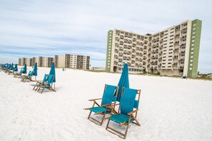 A beach with rows of wooden beach chairs and blue umbrellas, and a large hotel building in the background. - Views for miles Pinnacle Port Heated pool Check this out May & Summer (PANAMA CITY BEACH)
