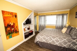 A bedroom with a bed, a painting, a TV, and a window with curtains. - Views for miles Pinnacle Port Heated pool Check this out May & Summer (PANAMA CITY BEACH)