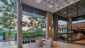 A spacious indoor area with large windows, a modern ceiling design, and a seating area with round tables and chairs. - The Park Nine Hotel Suvarnabhumi  (Bangkok)