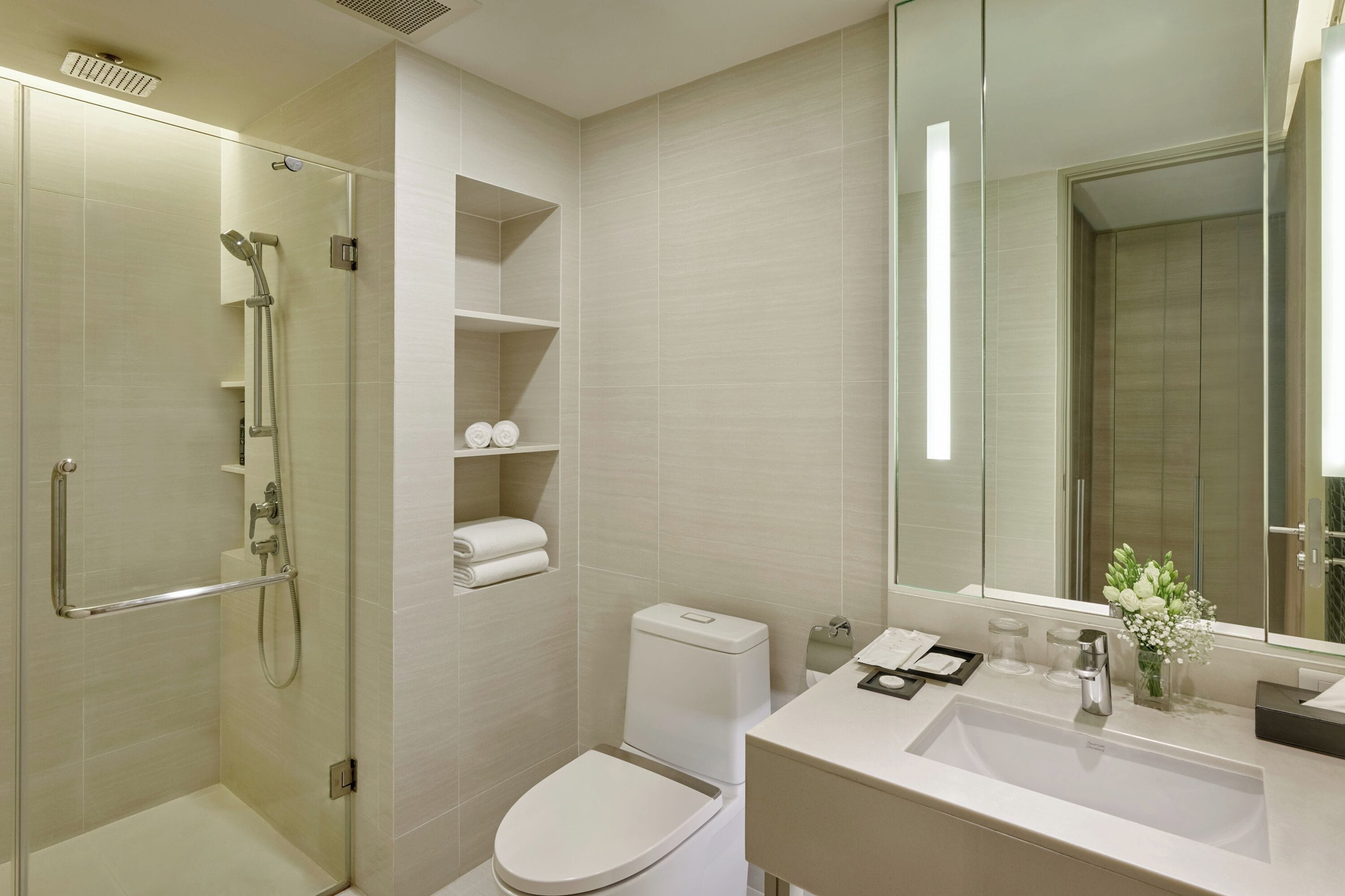 A modern bathroom with a glass-enclosed shower, a toilet, and a sink with a mirror above it.