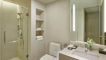 A modern bathroom with a glass-enclosed shower, a toilet, and a sink with a mirror above it.