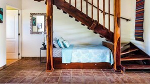 A bedroom with a wooden staircase, a bed with a blue blanket, and a small table with a plant. - La Cometa 19♆ Private rooftop terrace convenient in ♥ of town (Tamarindo)