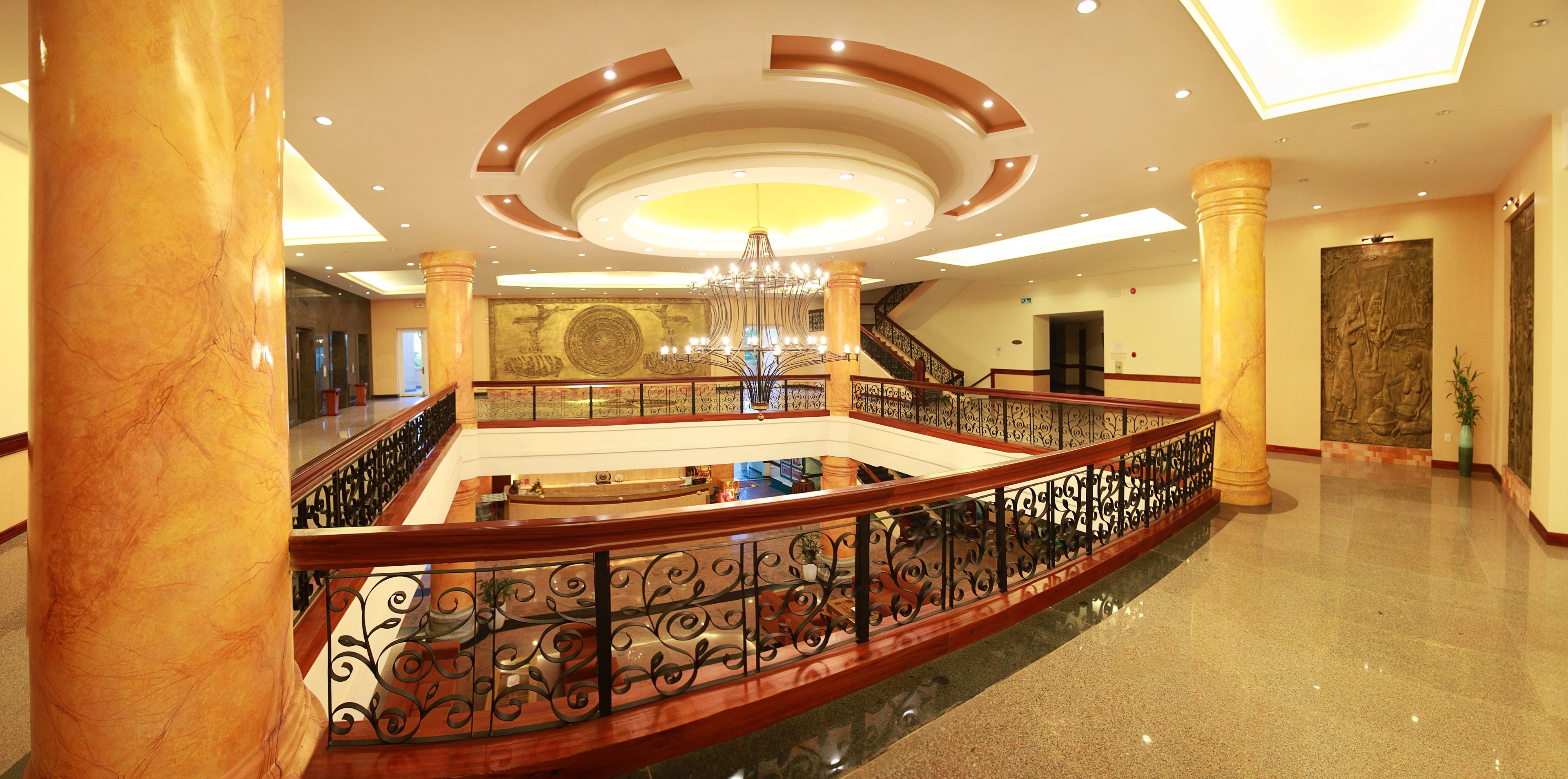 A spacious lobby with a central open area, a grand staircase, and a chandelier.
