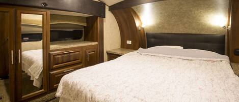 A bedroom with a bed, a vanity with a mirror, and a walk-in closet.