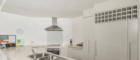 Una cocina moderna con un lavamanos de acero inoxidable, horno empotrado y un refrigerador grande.