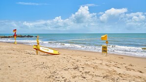 A beach with lifeguard flags, a yellow lifeguard stand, and a warning sign. - Peponi 4 - Beachfront Apartment (Yorkeys Knob)