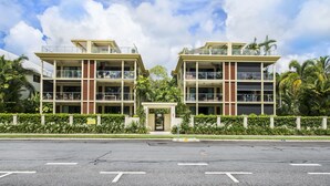 A modern building with multiple balconies, a central entrance, and surrounding greenery. - Peponi 4 - Beachfront Apartment (Yorkeys Knob)