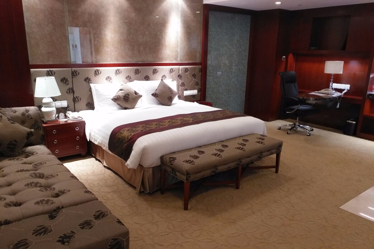 Ein Hotelzimmer mit einem großen Bett, einem Schreibtisch, einem Sessel und einem Sofa.