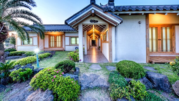 A traditional Japanese-style building with a covered walkway leading to the entrance. - Stone Statue Village Hanok (Seogwipo)