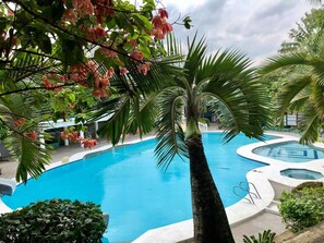 A swimming pool with a palm tree in the foreground and a view of the surrounding area. - V Resort Dasma (Dasmarinas)
