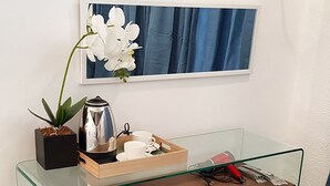 A modern glass desk with a wooden top, a black stool, a potted plant, a kettle, and a tray with cups and saucers. - V Resort Dasma (Dasmarinas)