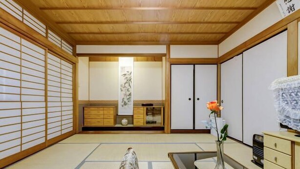 A traditional Japanese room with tatami flooring, a low wooden table, a cabinet, and a sliding door. - Nakayama Guesthouse (Osaka)