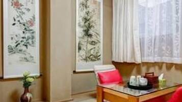 A traditional Japanese-style room with tatami flooring, a low wooden table, a red chair, and two large calligraphy paintings on the walls.