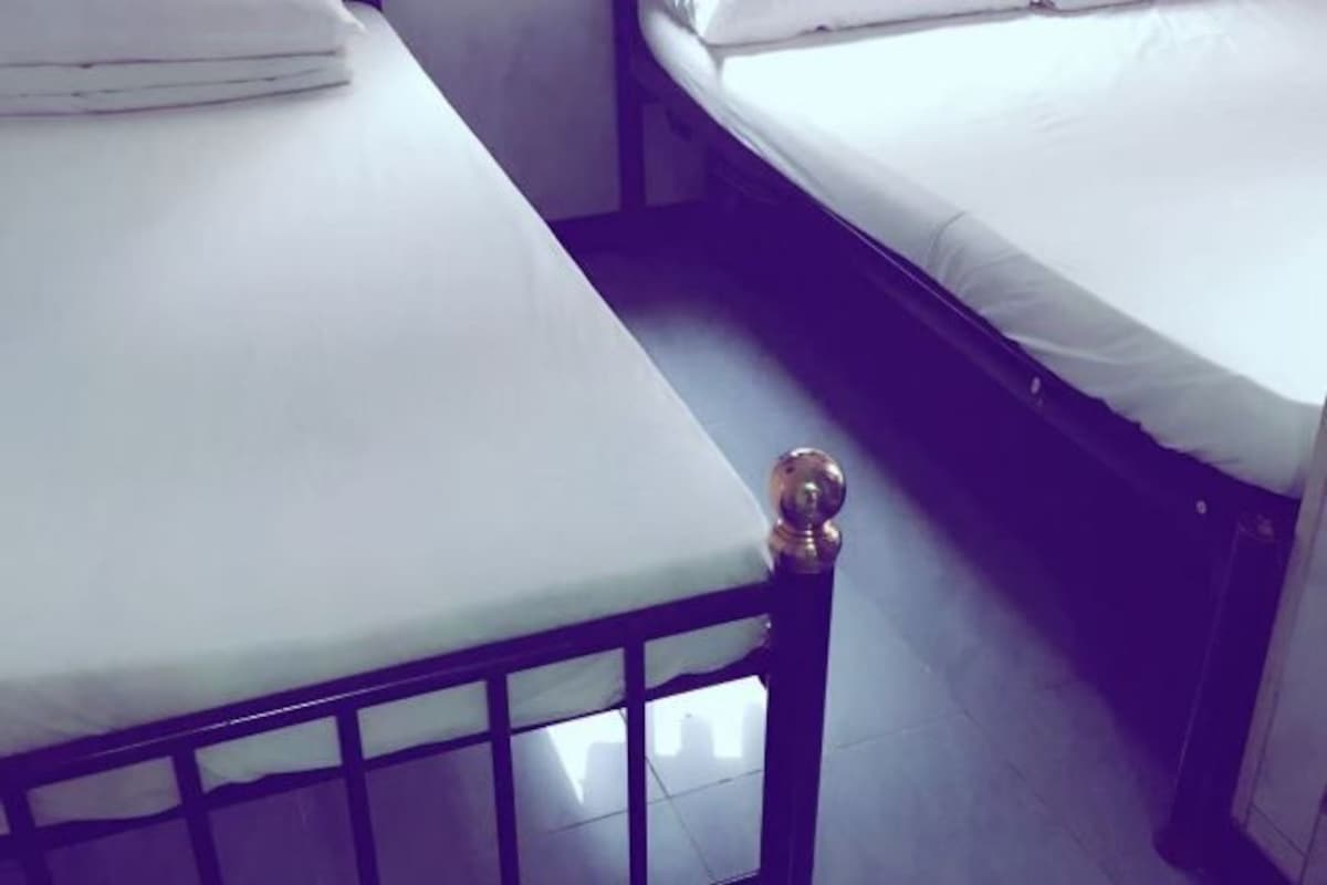 Quarto com duas camas, cada uma com roupa de cama branca e cabeceira de madeira.