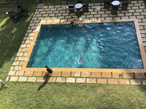 A rectangular pool with a tiled edge, surrounded by a brick border and grass.