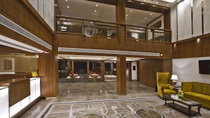 A spacious lobby with a high ceiling, wooden paneling, and a central open area with seating. - Alokik Resort (Manali)