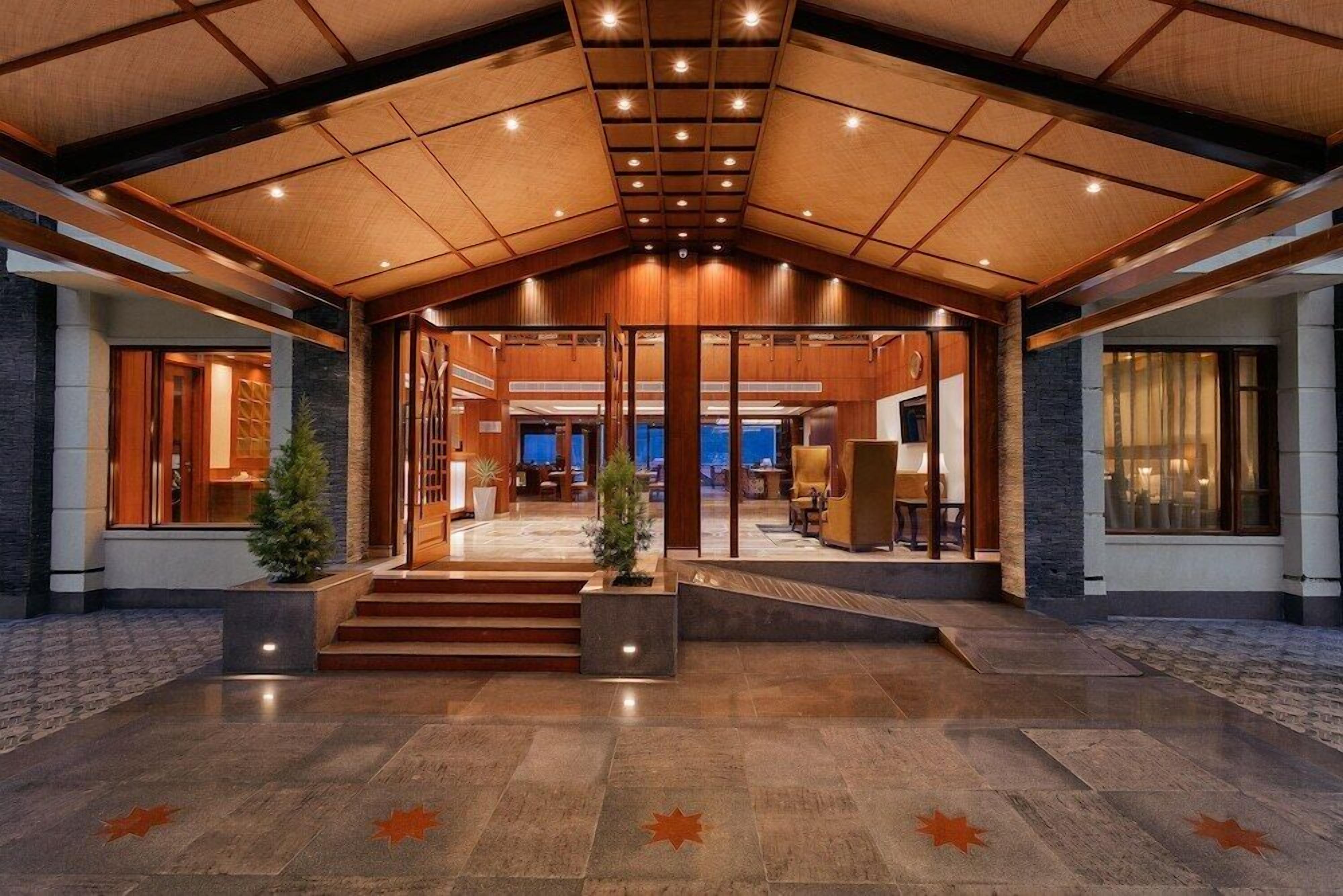 A spacious lobby with a high ceiling, wooden paneling, and a central staircase leading to upper floors.