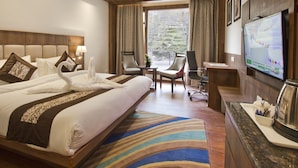 A hotel room with a large bed, two chairs, a desk, a television, and a view of the outdoors. - Alokik Resort (Manali)