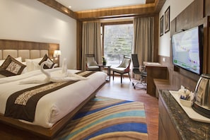 A hotel room with a large bed, two chairs, a desk, a television, and a view of the outdoors.